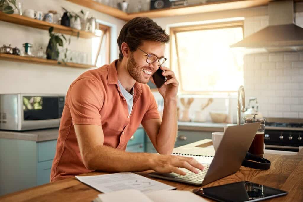 Man talks on phone and searches inpatient detox on laptop