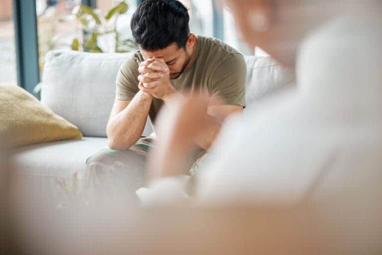 man with head in hands wonders about meth addiction causes