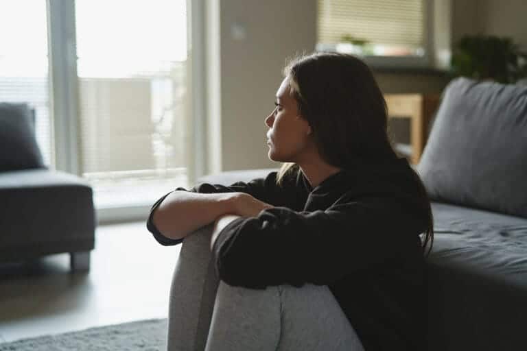 woman looking out of window wonders about heroin side effects